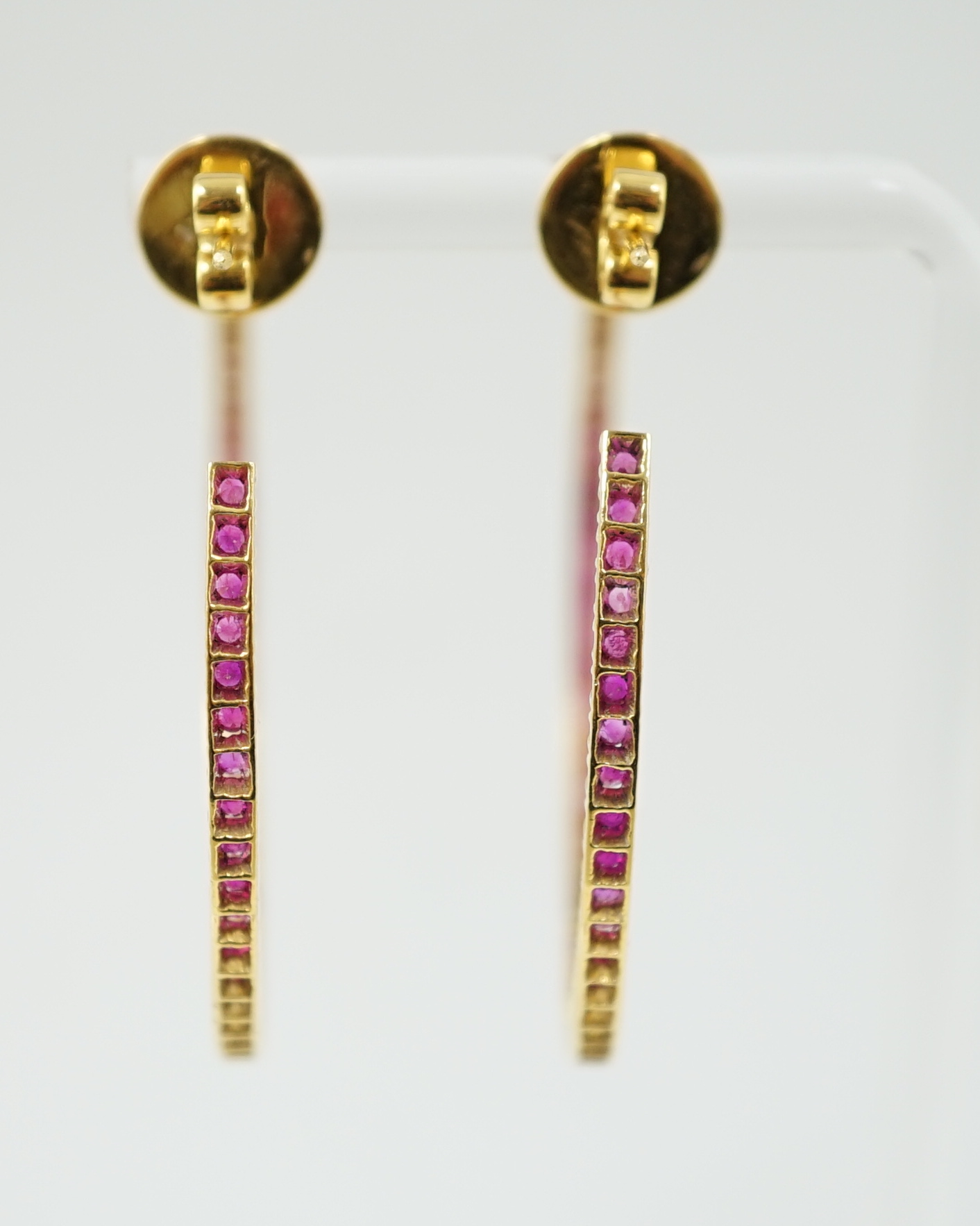 A large pair of gold and ruby chip set hoop earrings